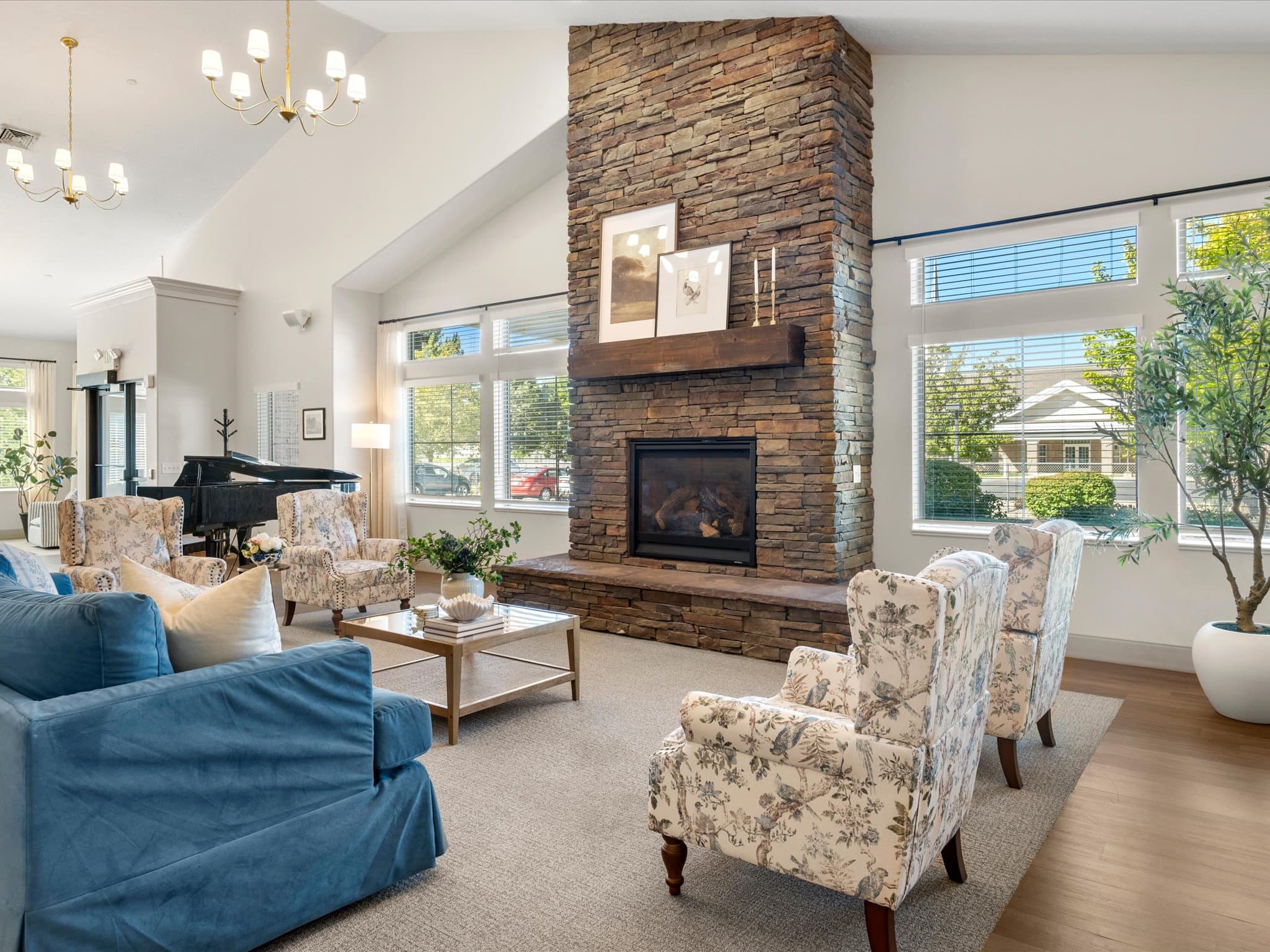 Great room fireplace with floral armchairs and a blue sofa