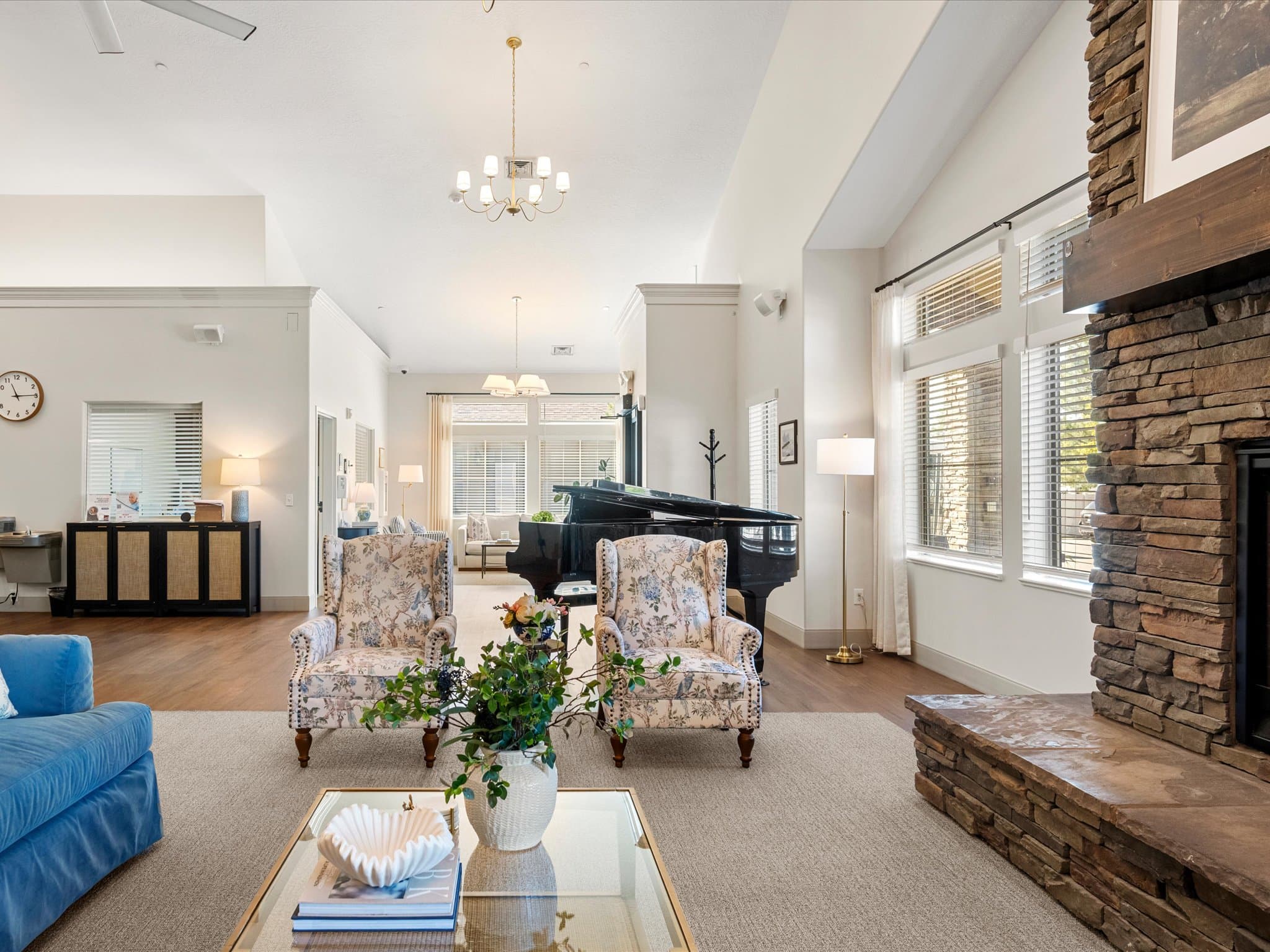 Great room with grand piano and floral seating near the entrance