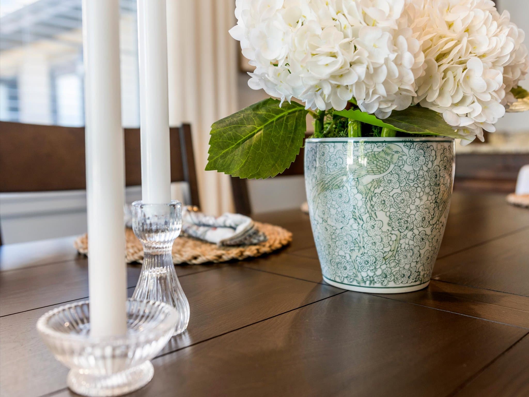 White hydrangea centerpiece and candlesticks set on a dining table