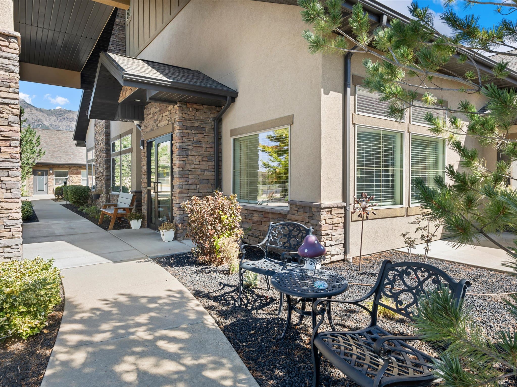 Side entrance with stone accents, walkway, and outdoor seating