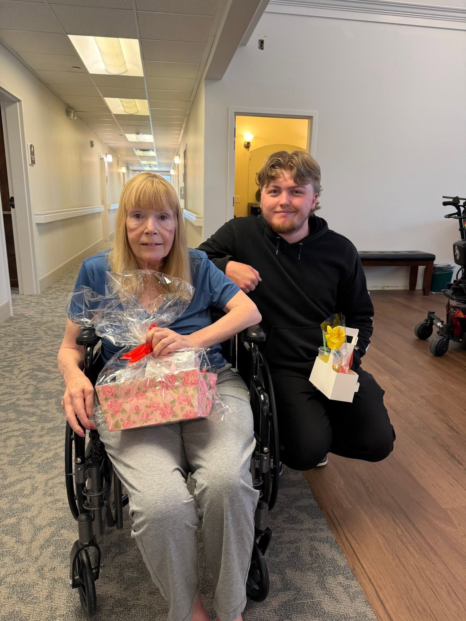 Resident and a family member holding gift baskets in the hallway during a community event